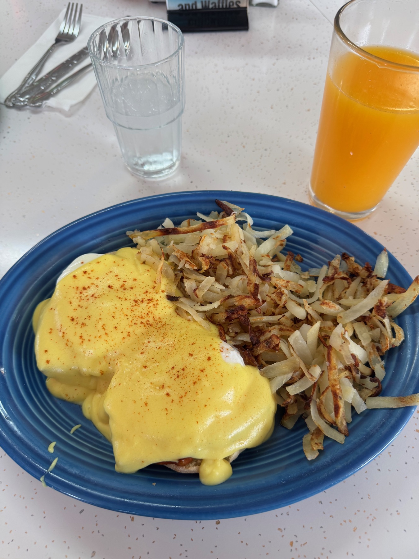 Eggs Benedict with hashbrowns and orange juice on a blue plate at the 101 Diner near Port Angeles