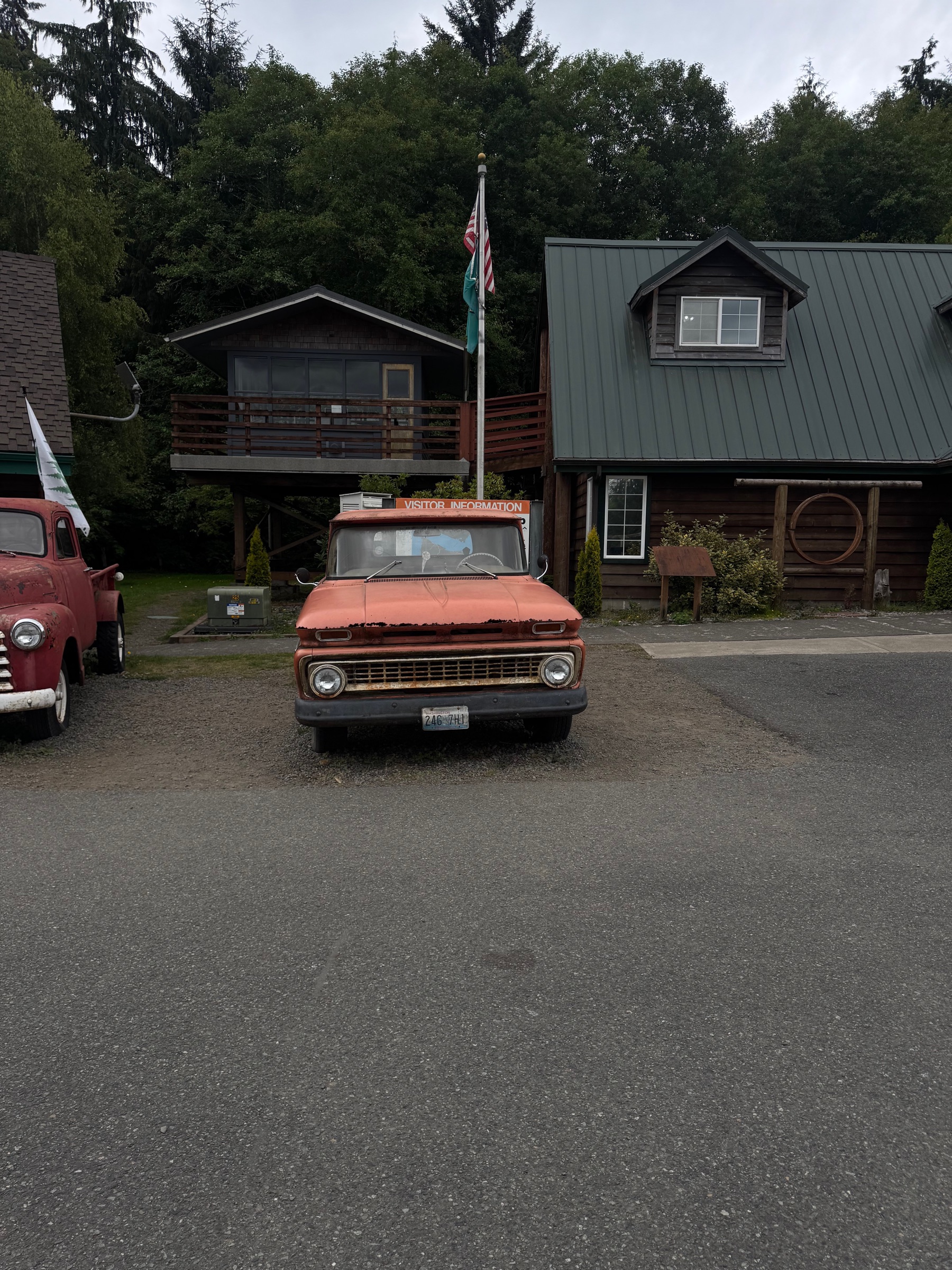 A vintage Chevrolet pickup truck parked in front of cedar cabins in Forks, Washington, on an overcast day